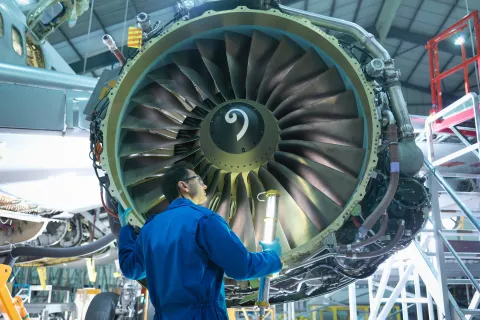 Engineer inspecting jet engine in aircraft maintenance factory