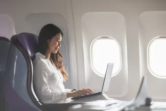 oung woman using laptop sitting near windows at first class on airplane during flight