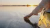 Slow traveler touching water from kayak during sunset