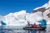Expedition travelers in a Zodiac inflatable boat cruising past icebergs in Antarctica